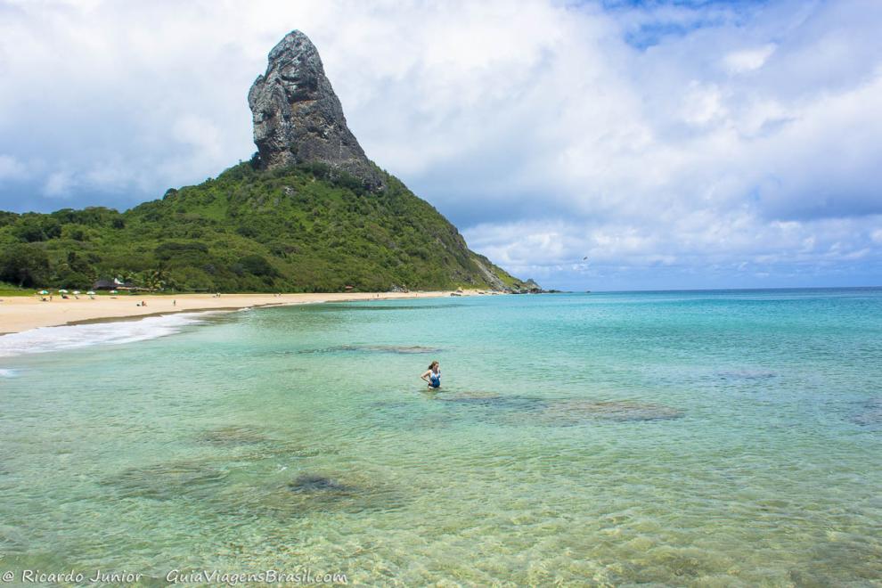 Imagem de uma mulher nas águas límpidas da Praia da Conceição.